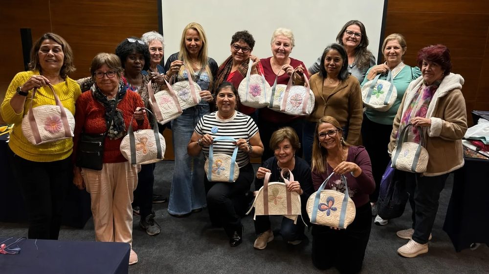 Turma de alunas da Márcia segurando as bolsas quiltadas que terminaram no evento