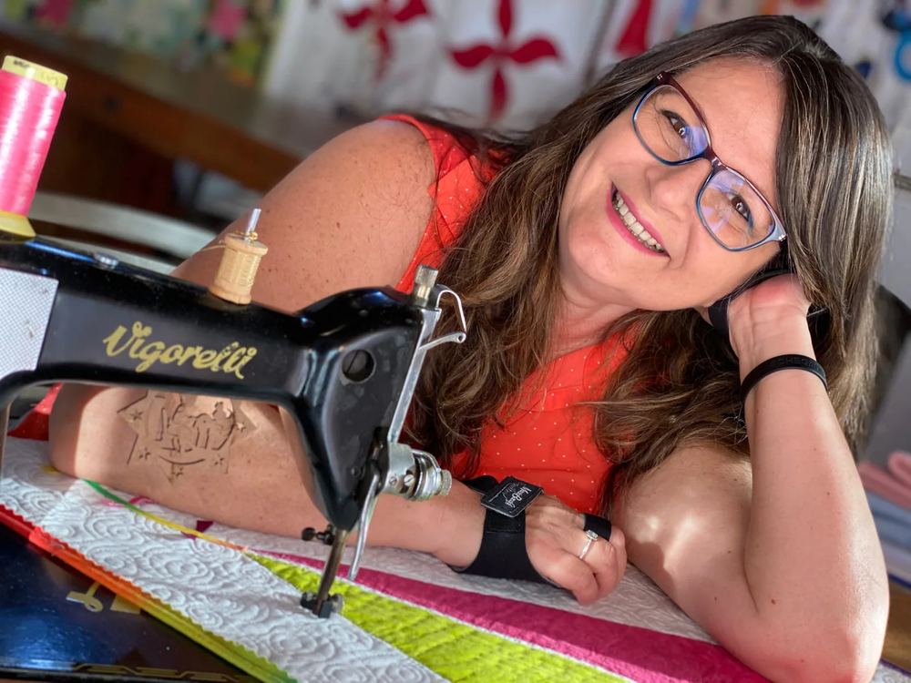 Márcia Baraldi sorrindo na sua máquina de costura Vigorelli, no ateliê
